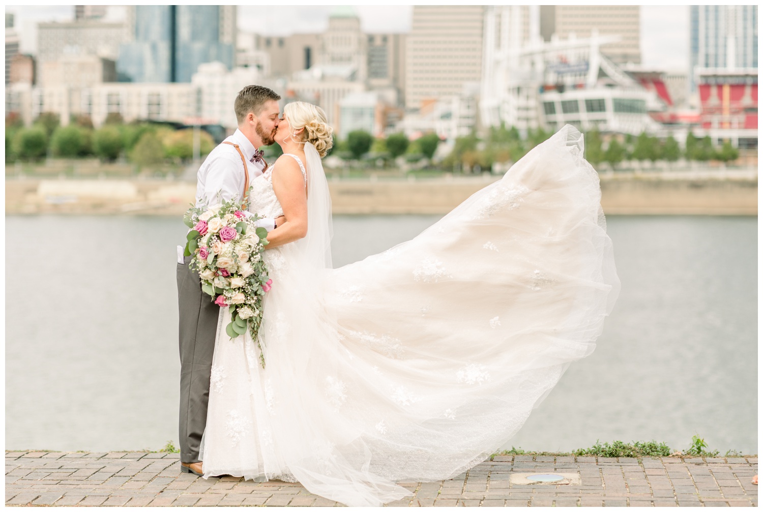 Bride and Groom with Wedding Dress Blowing in Wind with Cincinnati Skyline in Background