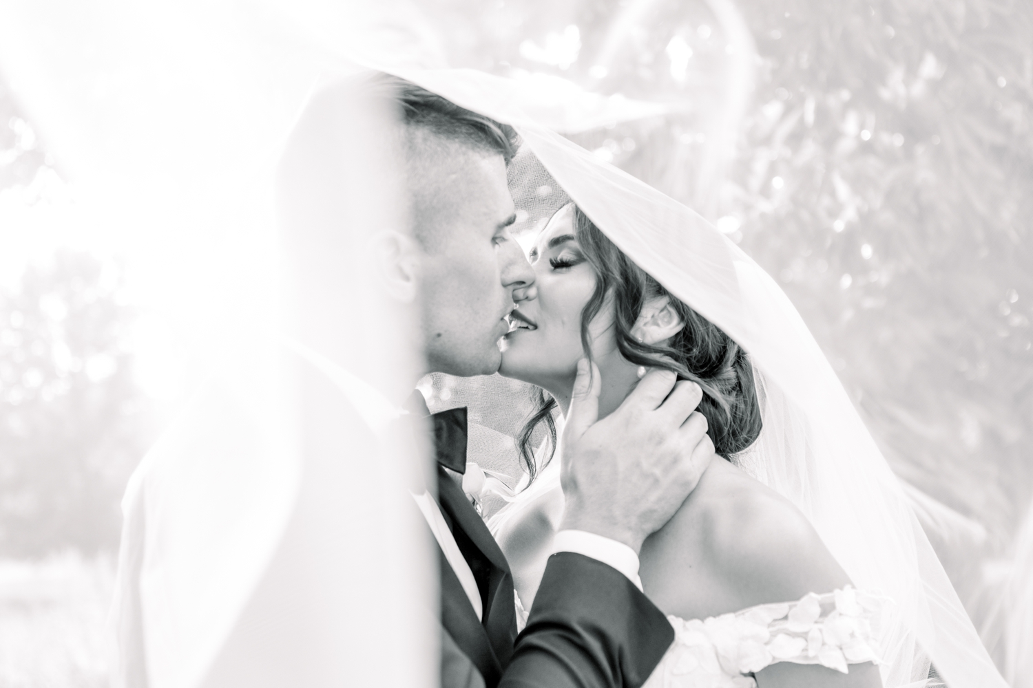 Bride and Groom Kissing Under Veil in Black and White